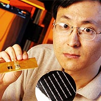 Graduate Research Assistant Bing Dang holds a silicon wafer containing chips built with microchannels, and (left) an organic printed circuit board with two microfluidic chips bonded to it. <BR><BR>Georgia Tech Photo: Gary Meek