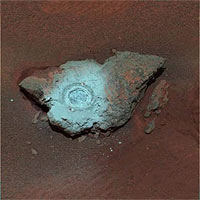 This false-color composite of the rock dubbed 'Bounce' shows the rock after the Mars Exploration Rover Spirit drilled into it with its rock abrasion tool. 
The drilling of the 7-millimeter-deep (0.3-inch) hole generated a bright powder. The color in this image has been enhanced to show that these tailings are relatively blue when compared with the unaltered rock (to the human eye, the tailings would appear red).
This image was assembled from the infrared (750-nanometer),
green (530-nanometer) and violet (430-nanometer) filters of the rover's panoramic camera. It was taken on sol 68.
<P>
Image Credit: NASA/JPL/Cornell