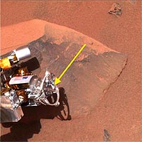 This image shows the Mars Exploration Rover Spirit's 'hand,' or the tip of the instrument deployment device, poised in front of the rock nicknamed Adirondack, the rover's first science target since developing communication problems over two weeks ago. In preparation for grinding into Adirondack, Spirit cleaned off a portion of the rock's surface with a stainless steel brush located on its rock abrasion tool and seen here at the end of the yellow arrow. The image was taken by the rover's panoramic camera. 
<P>
Image Credit: NASA/JPL/Cornell